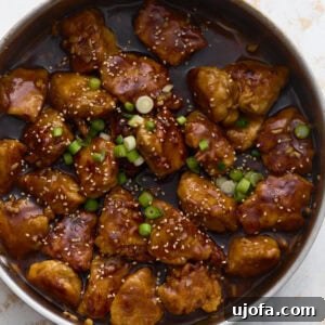 Flavorful Gluten-Free Chicken Feasts 15 Gluten-free General Tso’s chicken coated in a glossy sweet and spicy sauce, garnished with green onions and sesame seeds in a skillet.