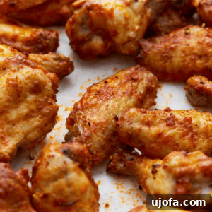 Flavorful Gluten-Free Chicken Feasts 4 Closeup of a tray of crispy, golden-brown gluten-free chicken wings seasoned with spices and arranged on parchment paper, showing their lightly charred edges and flavorful coating.