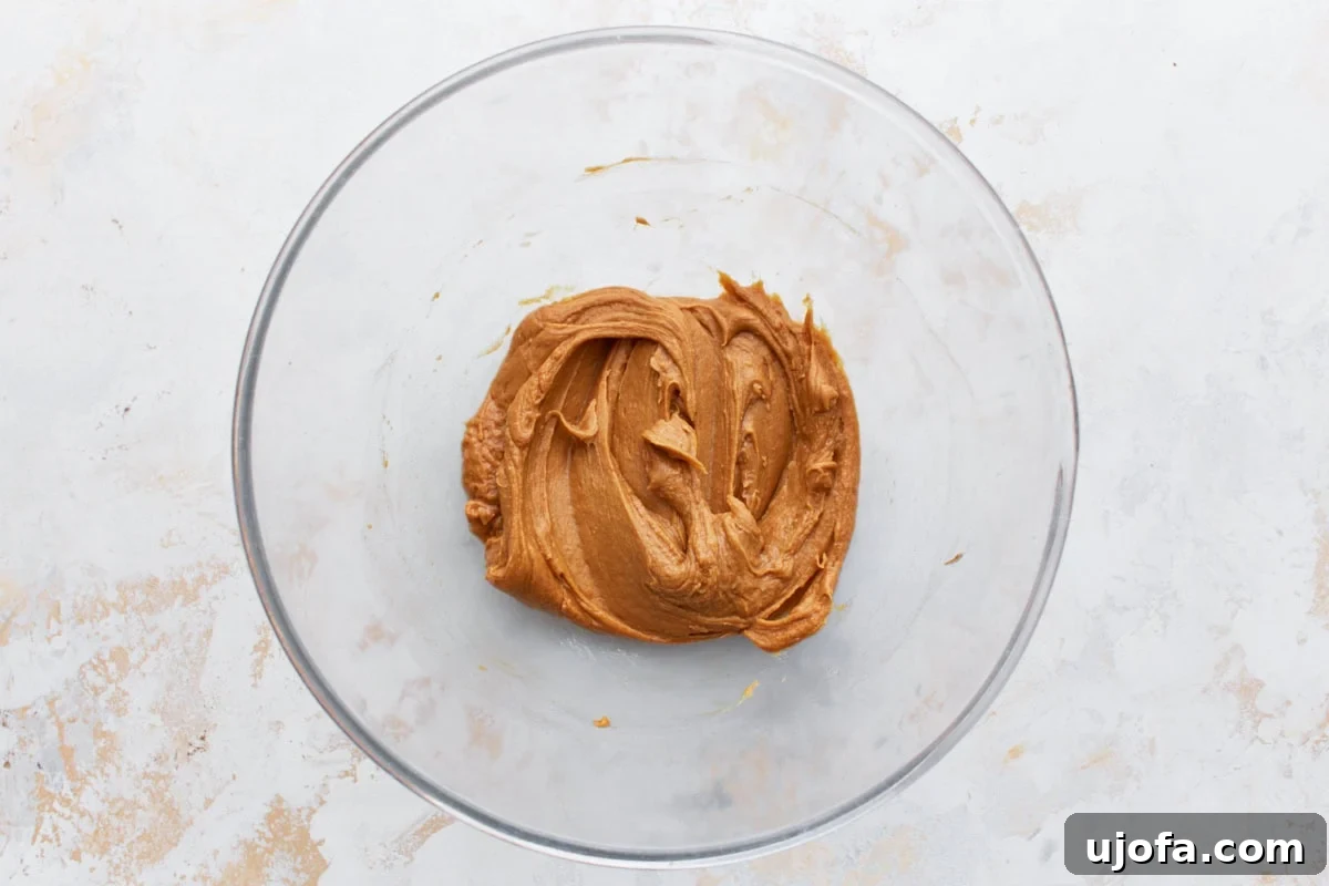 Creamy peanut butter mixture in a glass bowl, the base for homemade gluten-free granola bars, showing its smooth consistency.