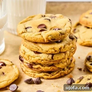 A stack of gluten-free chocolate chip cookies on parchment paper, surrounded by other cookies.