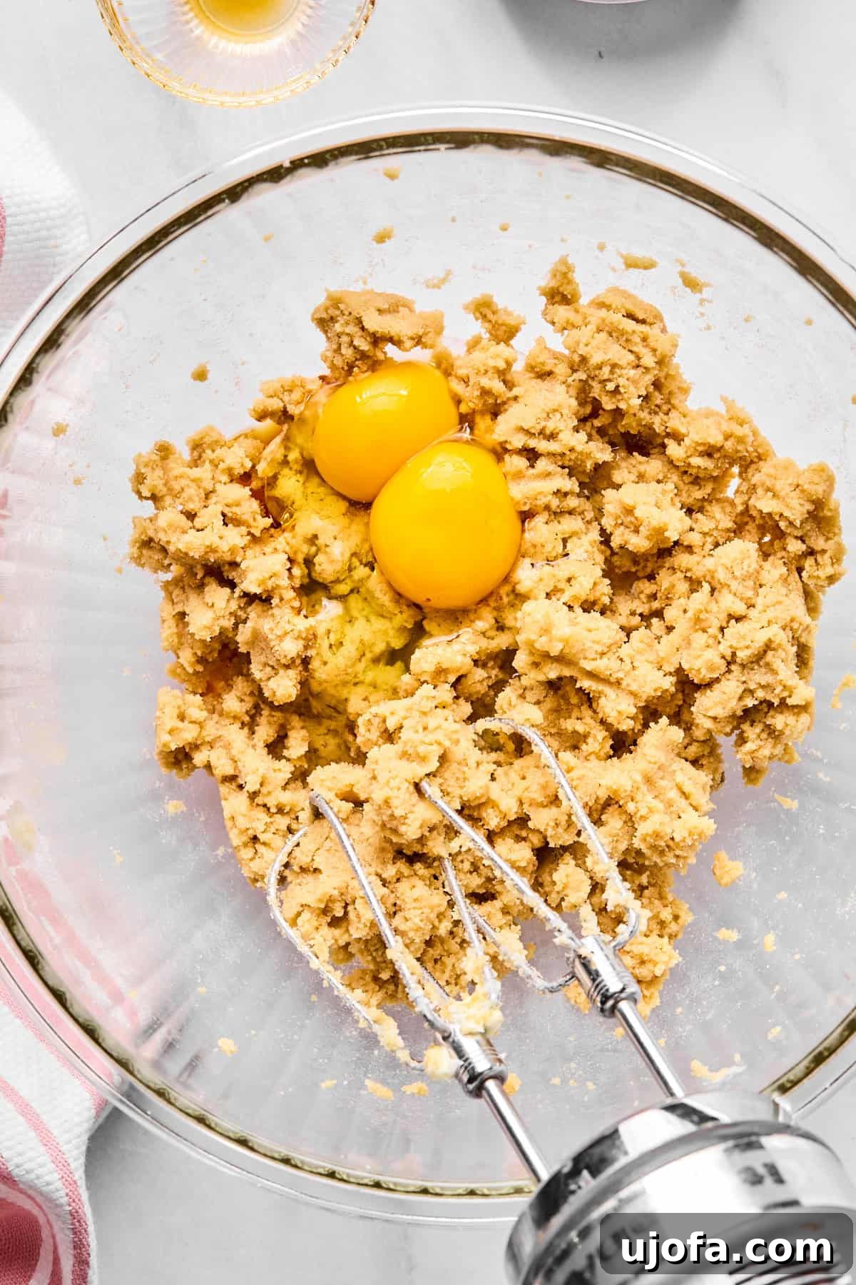 Creamed butter and both granulated and brown sugars in a larger mixing bowl, with two eggs beside it.