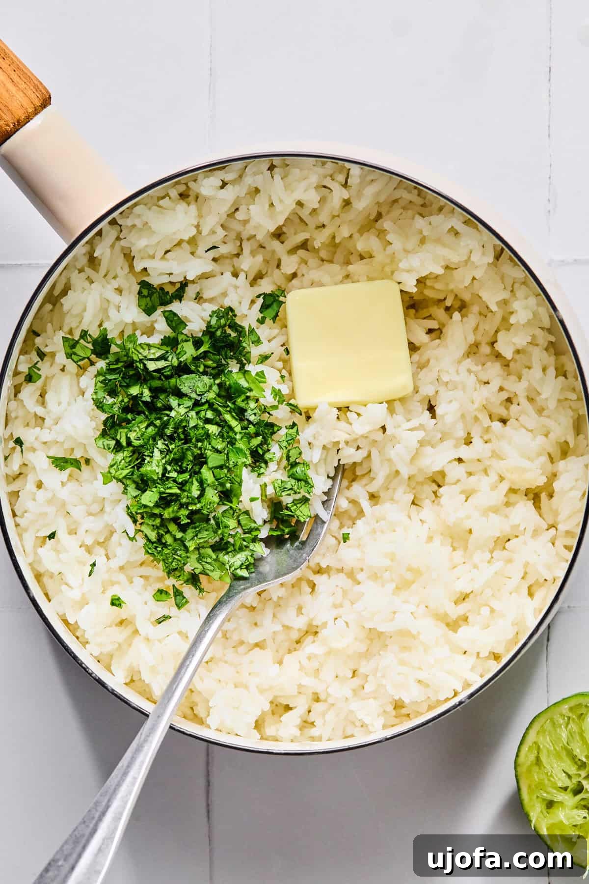 Fluffy cilantro lime rice being mixed with butter, salt, and fresh lime juice in a saucepan, ensuring every grain is coated with flavor.