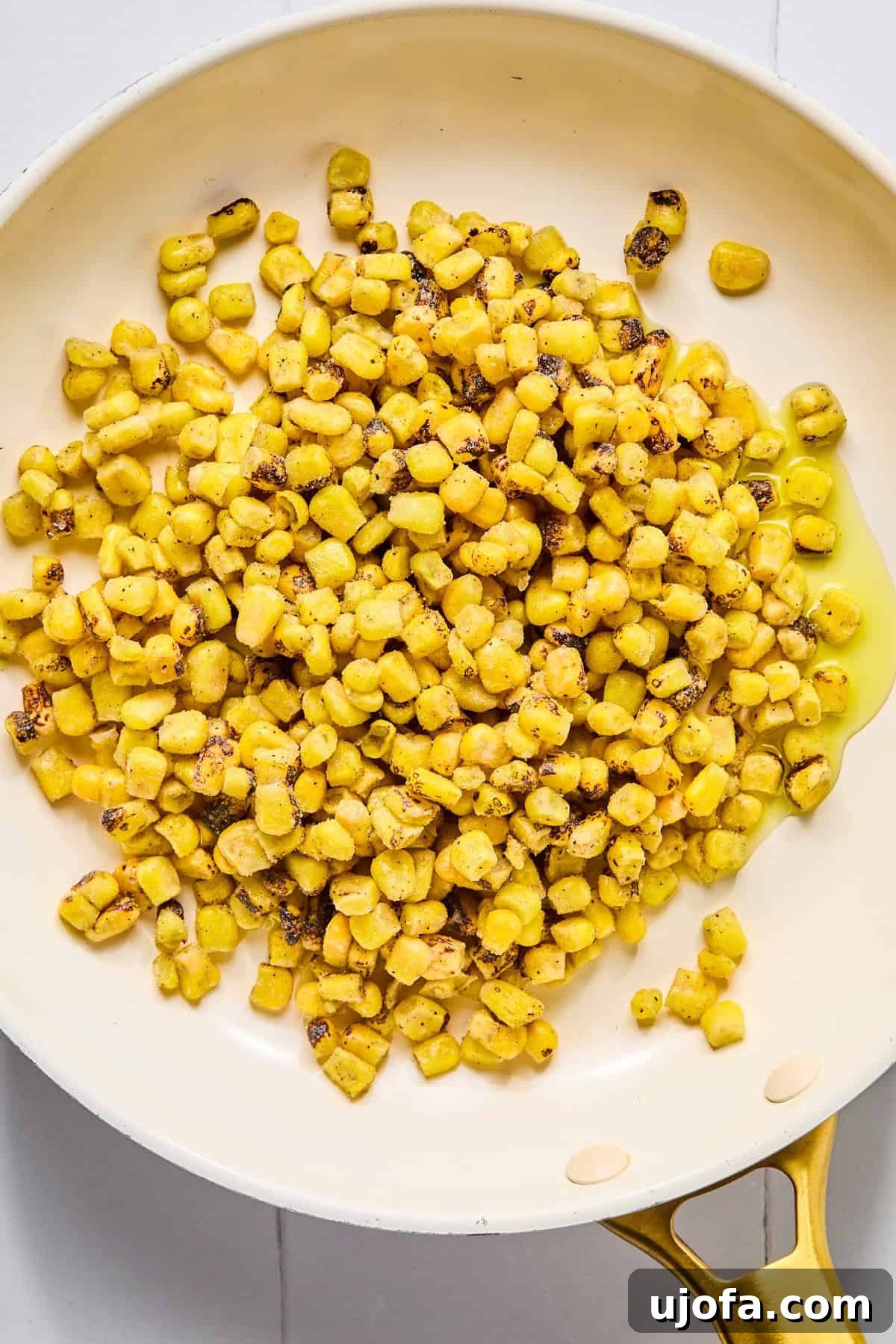 Corn kernels charring beautifully in a hot skillet with olive oil, developing a smoky flavor before being mixed into the creamy street corn.