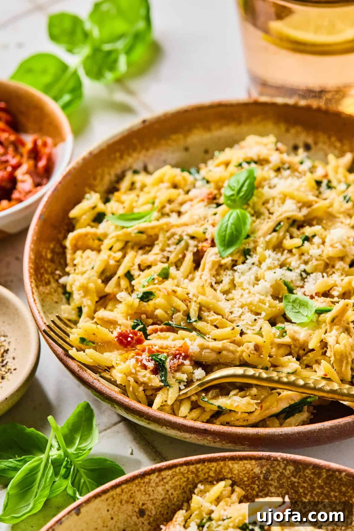 Marry Me Chicken Orzo served in a bowl with a fork, garnished with fresh basil leaves.