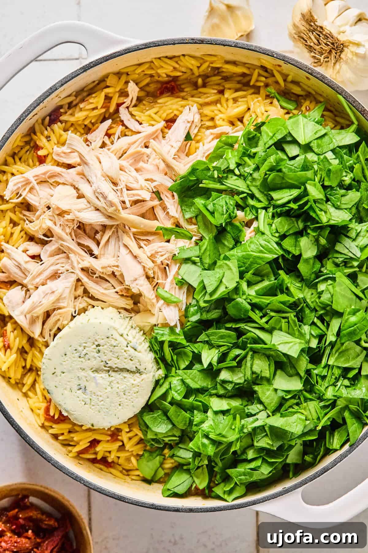Cooked chicken, spinach, and Boursin cheese in the skillet with the creamy orzo.