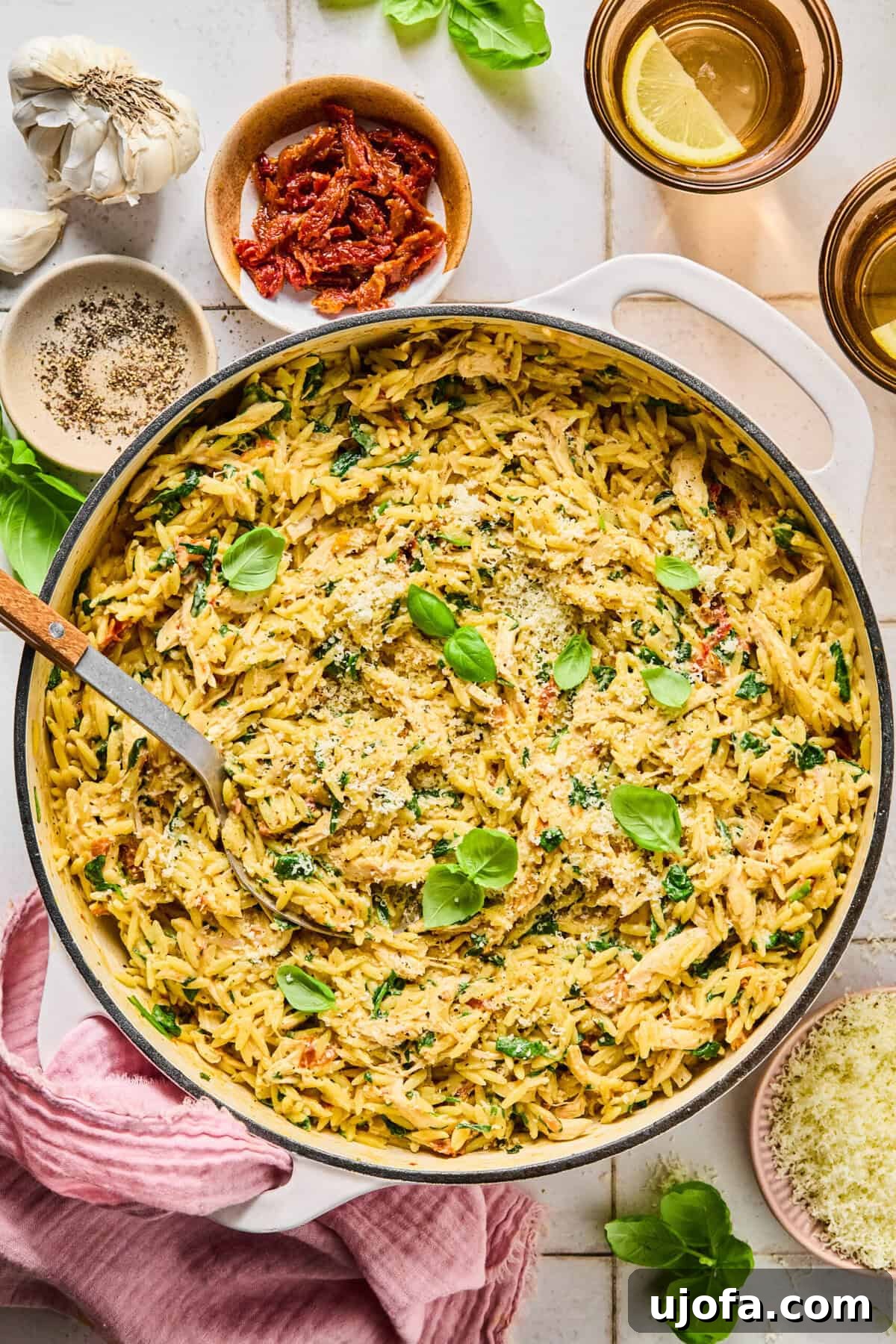 One-pan marry me chicken orzo in a skillet with ingredients arranged around the pan.