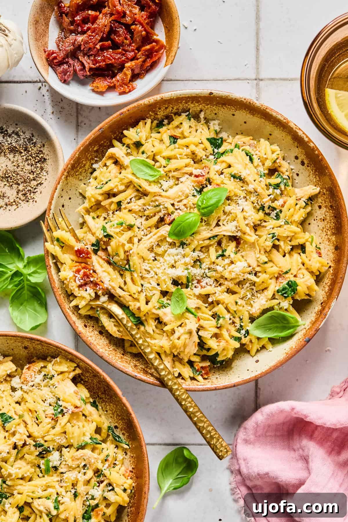 Birds eye view of creamy gluten-free marry me chicken orzo topped with fresh basil and grated parmesan in a bowl.