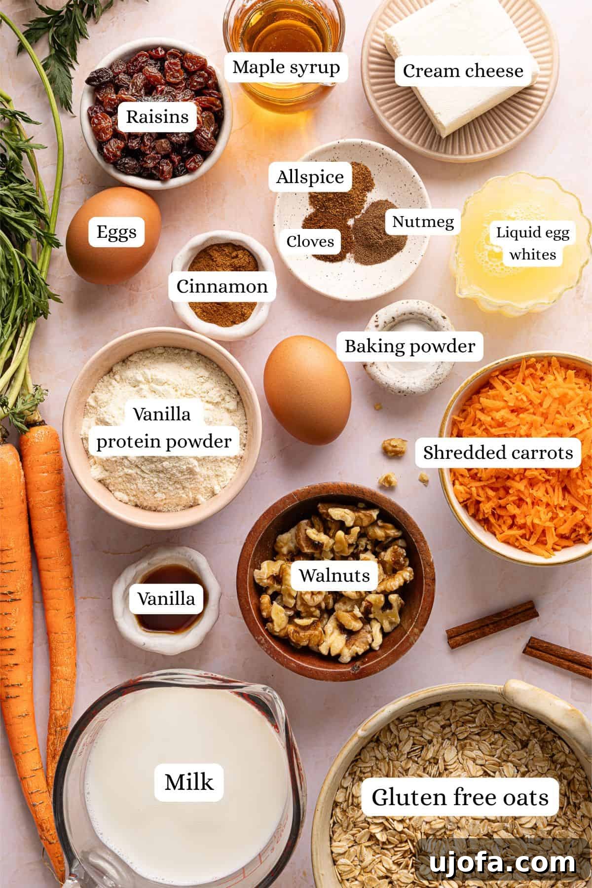 Protein-Packed Carrot Cake Oatmeal Bake 3 Ingredients for carrot cake baked oats labeled and laid out in nesting bowls on a light pink countertop.