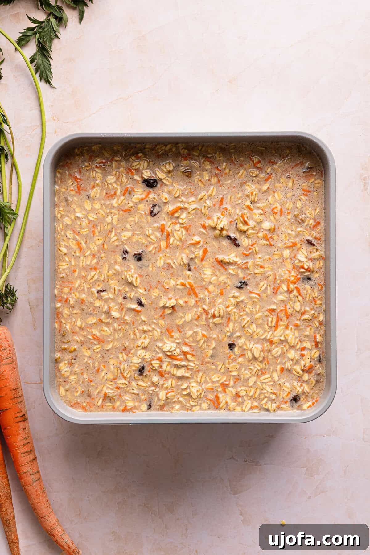 Protein-Packed Carrot Cake Oatmeal Bake 7 Carrot cake baked oats batter poured into a greased 9x9 metal baking dish before baking.