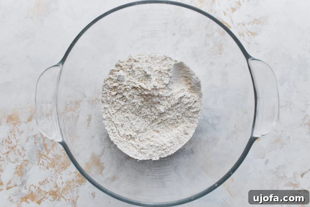 Pillowy Gluten-Free Beignets 5 A glass mixing bowl filled with a blend of gluten-free flour, yeast, sugar, and salt.