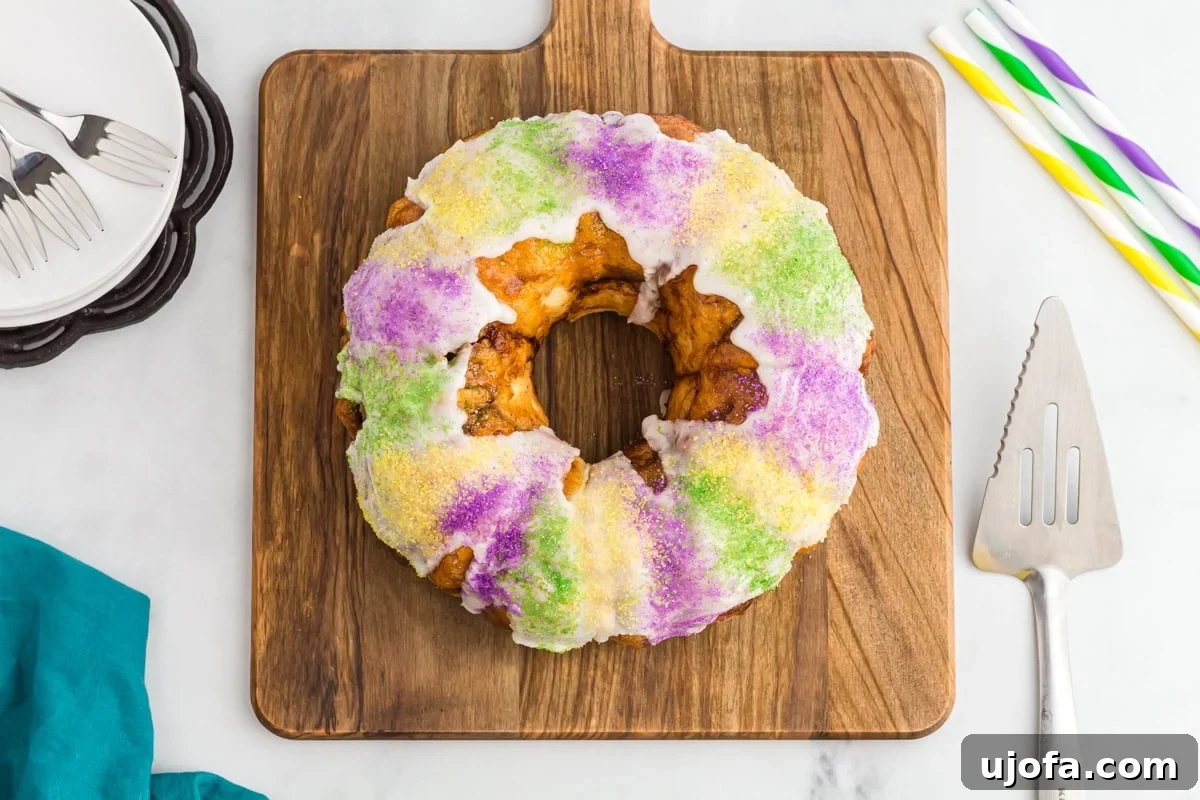 Mardi Gras Magic: Gluten-Free King Cake 17 Gluten free king cake topped with vanilla glaze and purple, yellow, and green sanding sugars on a wooden board.