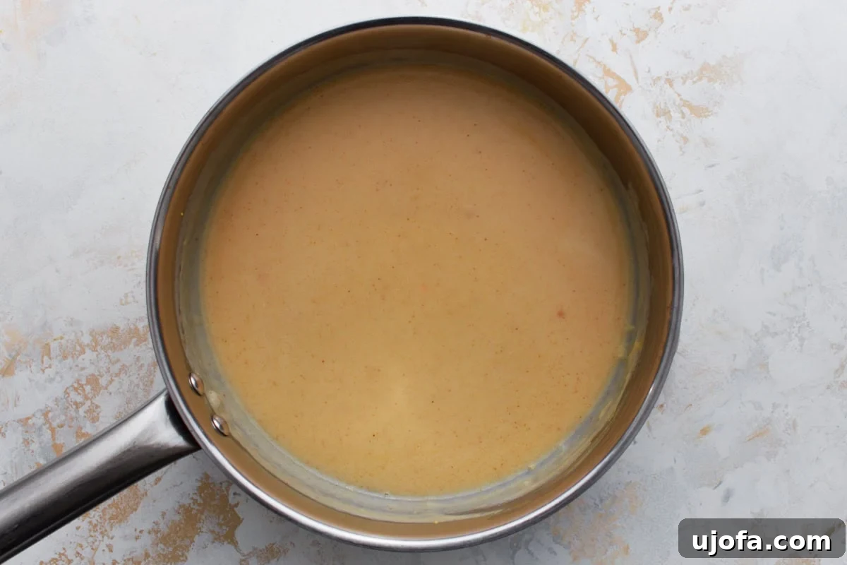 spices being stirred into gluten-free beer cheese sauce in a saucepan
