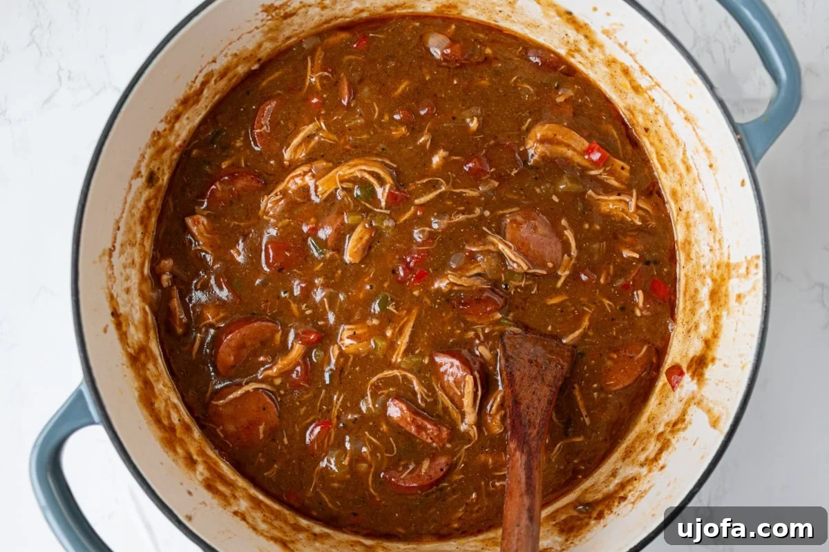 Delectable Gluten-Free Gumbo 14 The gluten-free chicken and sausage gumbo, now a deep, rich brown, simmering gently in the Dutch oven, indicating full flavor development.