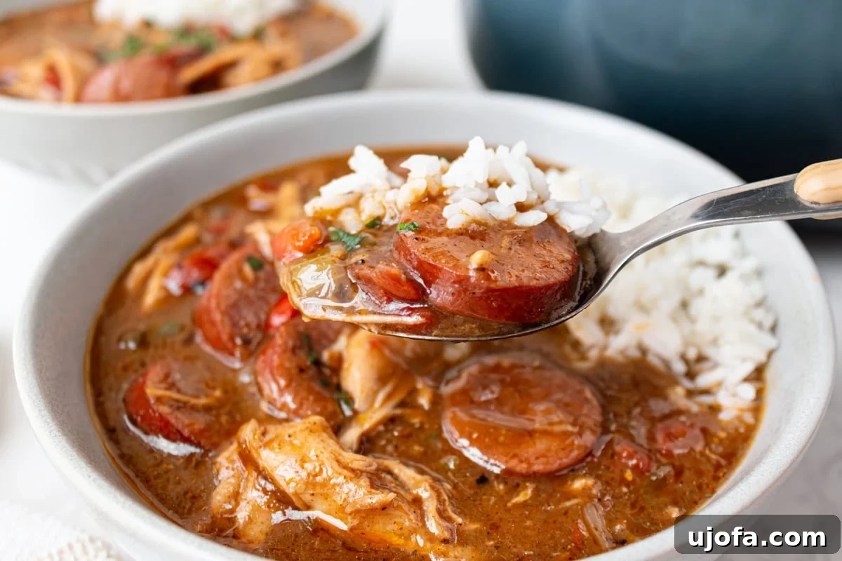 Delectable Gluten-Free Gumbo 16 A spoonful of gluten-free chicken and sausage gumbo, laden with meat, vegetables, and rice, lifted from a full bowl, showcasing its rich texture.