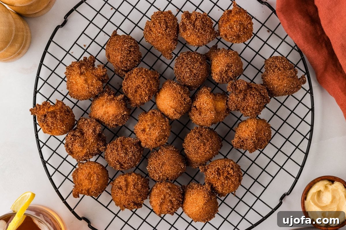 Gluten free hush puppies arranged on a cooling rack with dipping sauce nearby.