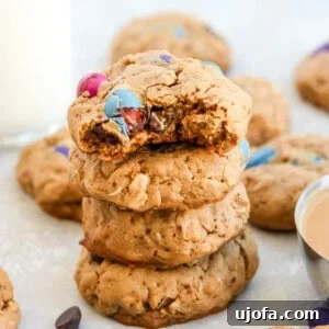 4 monster cookies stacked on top of each other surrounded by m&ms and other cookies