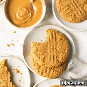 gluten free peanut butter cookies on small white plates with a bowl of creamy peanut butter and a white napkin