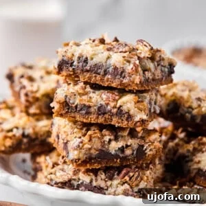 Close-up of a stack of gluten-free magic bar squares showing defined layers of chocolate, coconut, and pecans