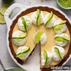Gluten free key lime pie in a white Staub pie plate surrounded by ingredients with a slice taken out