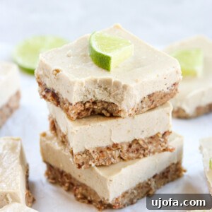 Vegan key lime cheesecake bars stacked on top of each other with a lime slice on top