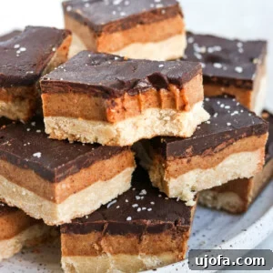 Vegan gluten free millionaire shortbread bars stacked on a plate. One has a bite out of it