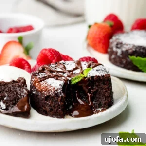 mini chocolate lava cake on a plate with mint leaves and raspberries and strawberries in the background