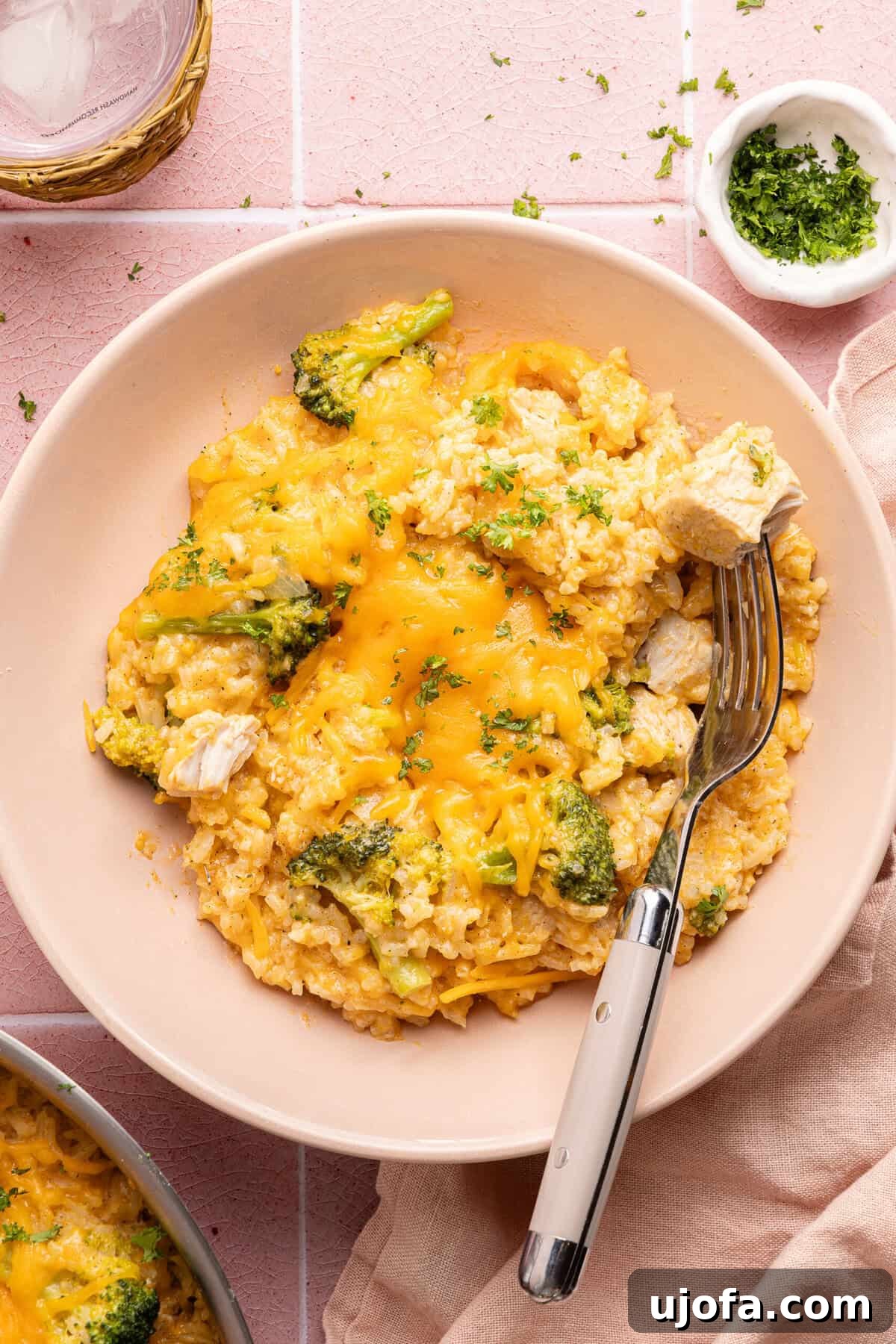 Ultimate Chicken Broccoli Rice Bake 11 A vibrant pink bowl filled with a generous serving of cheesy chicken broccoli rice casserole, showcasing its creamy texture and fresh ingredients.