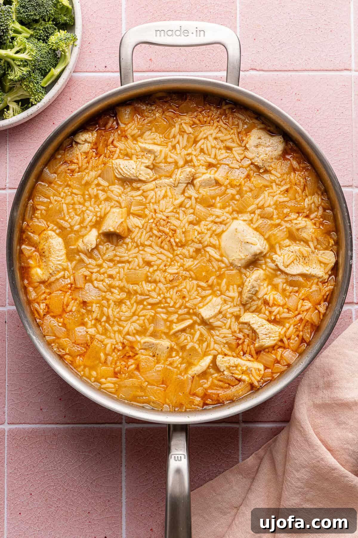 Ultimate Chicken Broccoli Rice Bake 6 A mix of chicken, uncooked rice, chicken broth, and seasonings simmering together in a large pan.