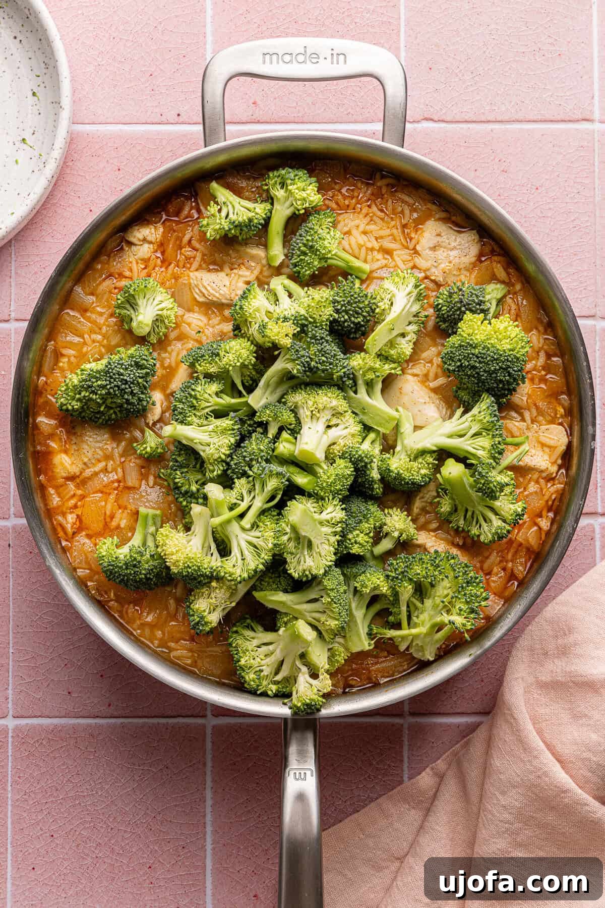 Ultimate Chicken Broccoli Rice Bake 7 Broccoli florets added to the simmering chicken and rice mixture in a pan, before being covered to finish cooking.