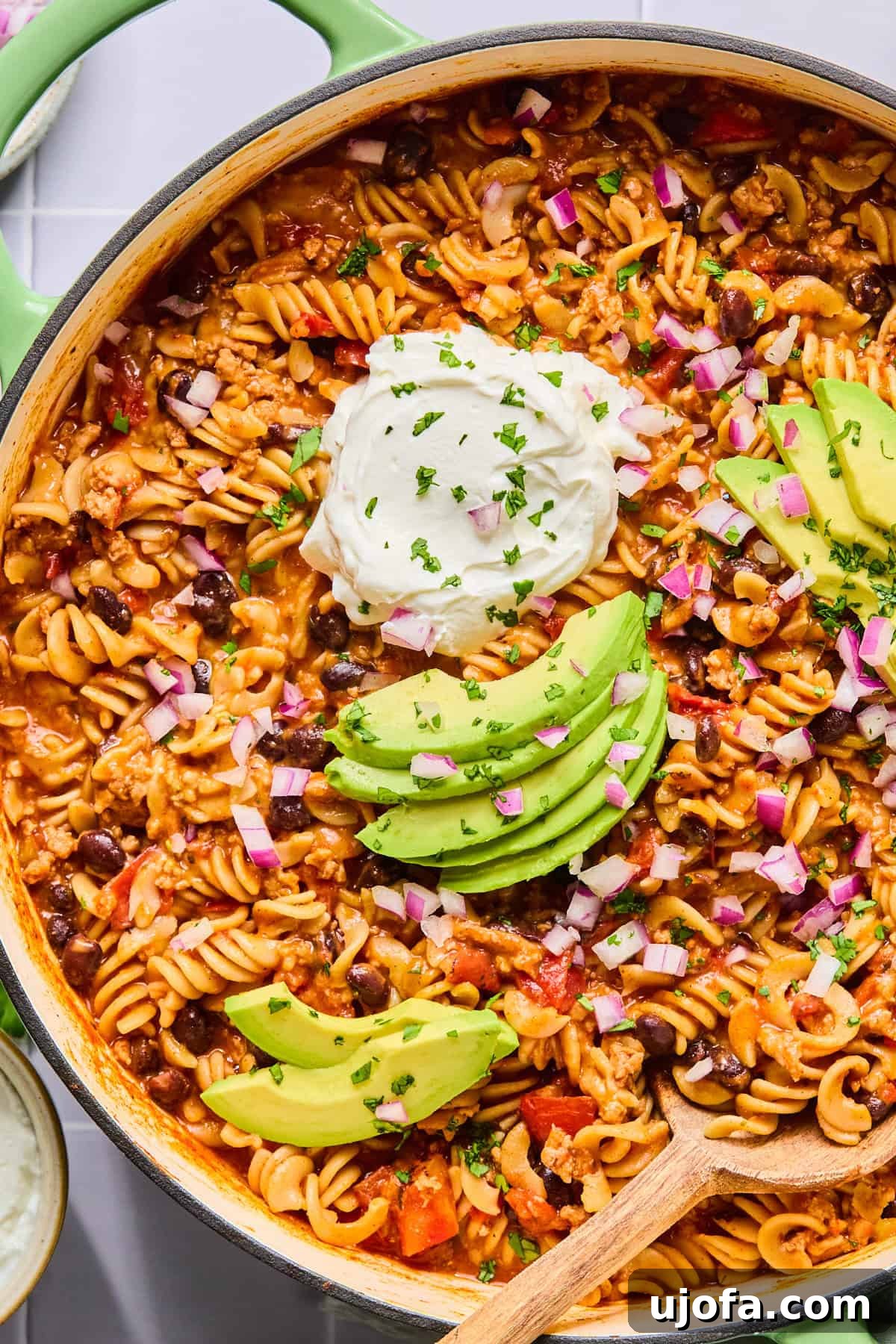 Close-up of one pot taco pasta topped with avocado slices, sour cream, and fresh cilantro, highlighting its creamy texture.
