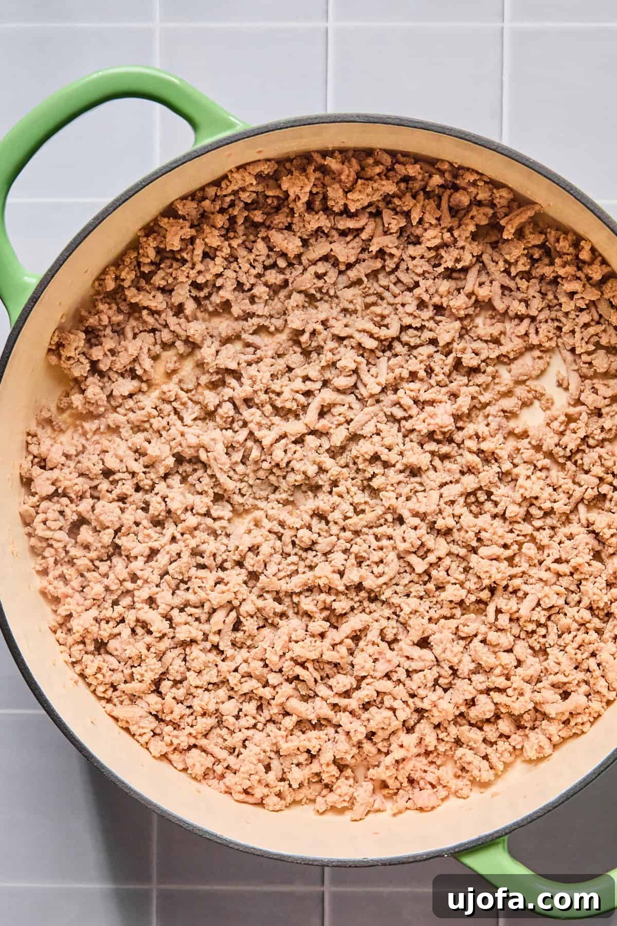 Ground turkey cooking in olive oil in a large skillet, broken up and browned until no longer pink.