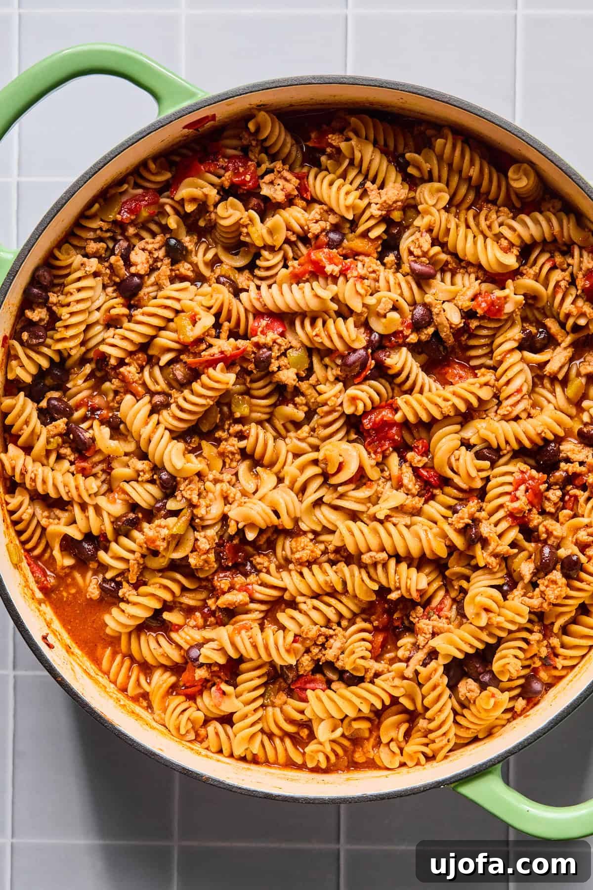 One pot taco pasta simmering in broth as the pasta cooks and absorbs the savory sauce, developing a rich, creamy consistency.