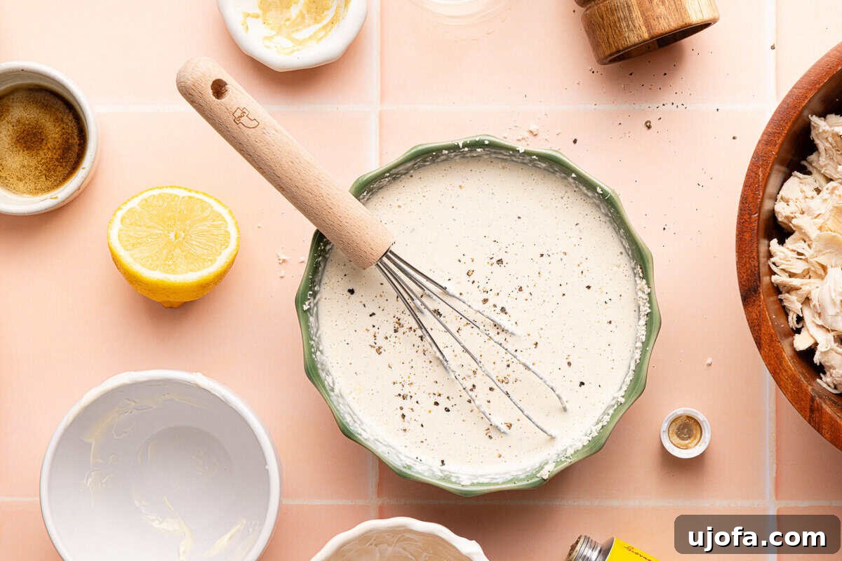 Effortless Gluten-Free Chicken Caesar Pasta Salad 5 homemade caesar dressing in a bowl with a whisk surrounded by ingredients
