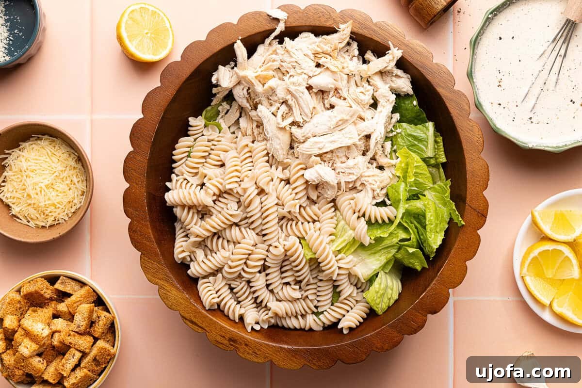 Effortless Gluten-Free Chicken Caesar Pasta Salad 6 pasta, chicken, and lettuce in a wooden bowl