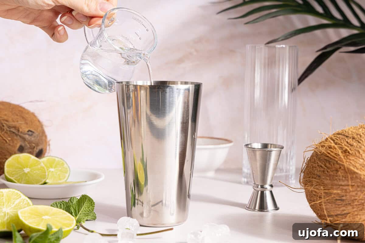 Dreamy Coconut Mojito 6 White rum being poured into a cocktail shaker filled with ice, ready to be mixed with cream of coconut.
