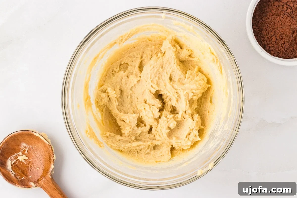 A bowl of light and fluffy creamed butter, granulated sugar, and brown sugar, mixed until smooth.