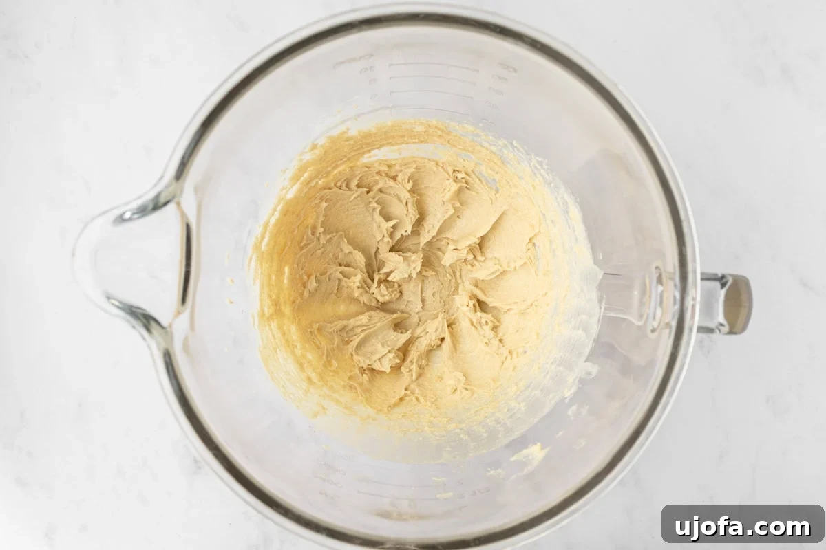 A mixing bowl containing creamed butter and light brown sugar, light and fluffy in texture, indicating they've been properly beaten.