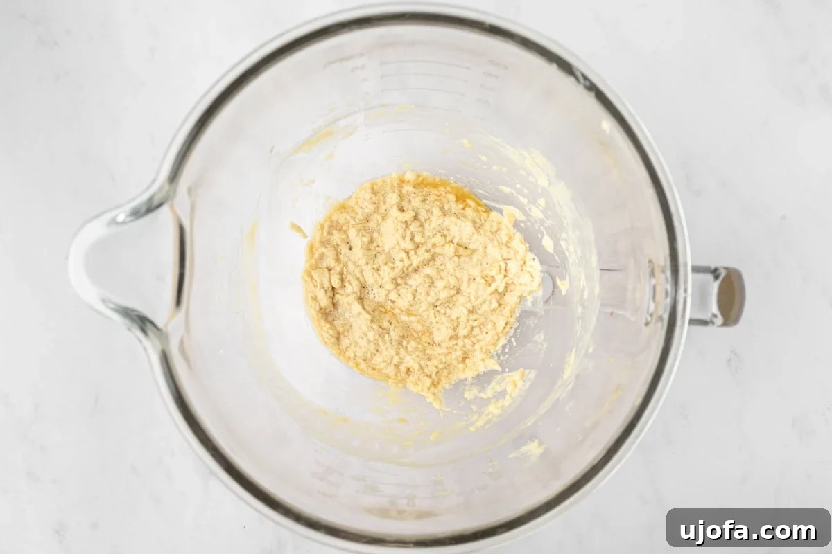 A mixing bowl filled with the combined wet ingredients for gluten-free animal cracker dough, showing a slightly curdled appearance which is normal at this stage.