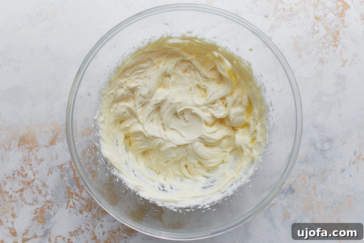 Cream cheese frosting whipped until light, smooth, and creamy in a glass mixing bowl.