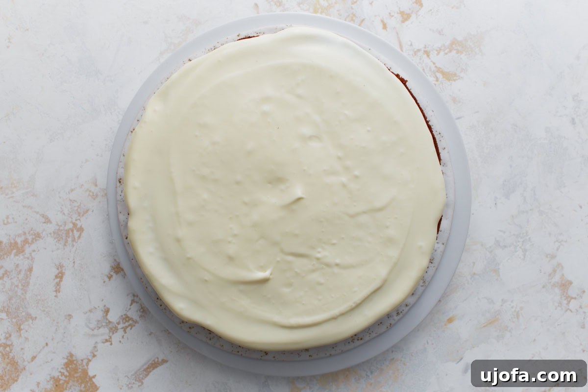 Almond flour carrot cake fully frosted with smooth cream cheese frosting spread evenly over the top.