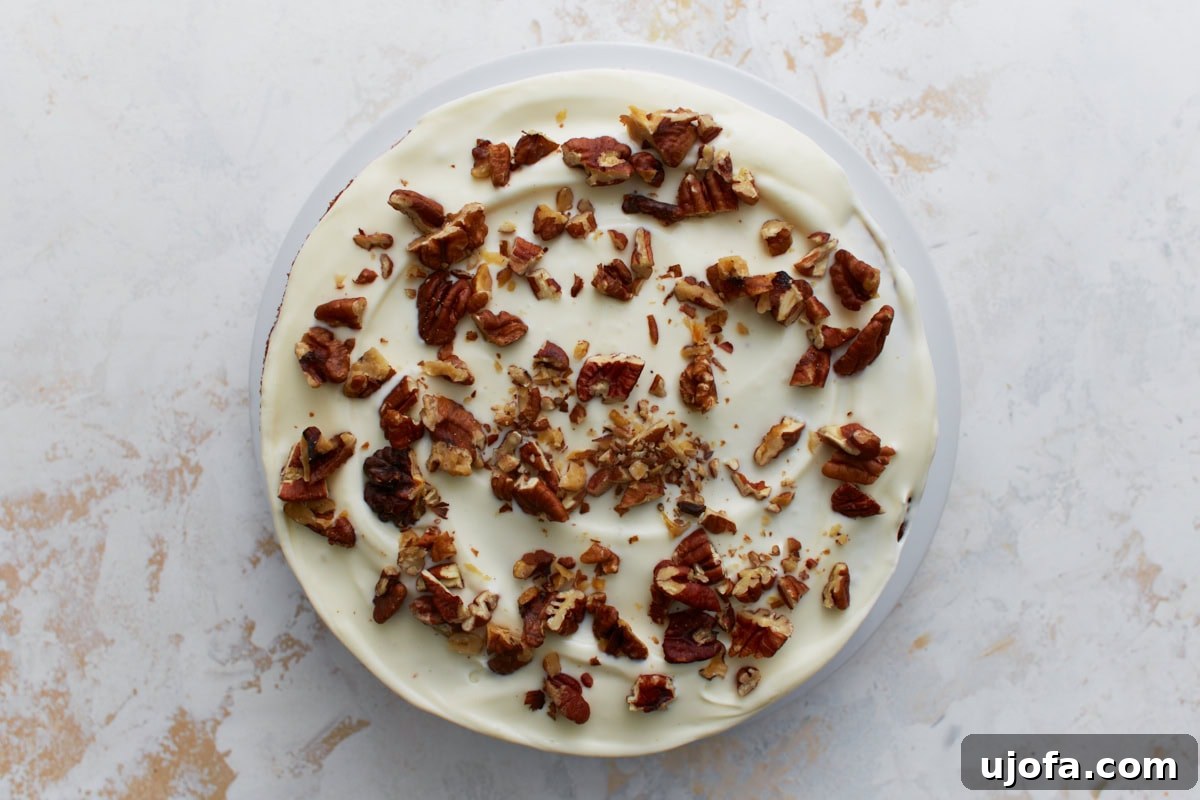 Almond flour carrot cake frosted with cream cheese frosting and topped with chopped pecans, photographed from above.