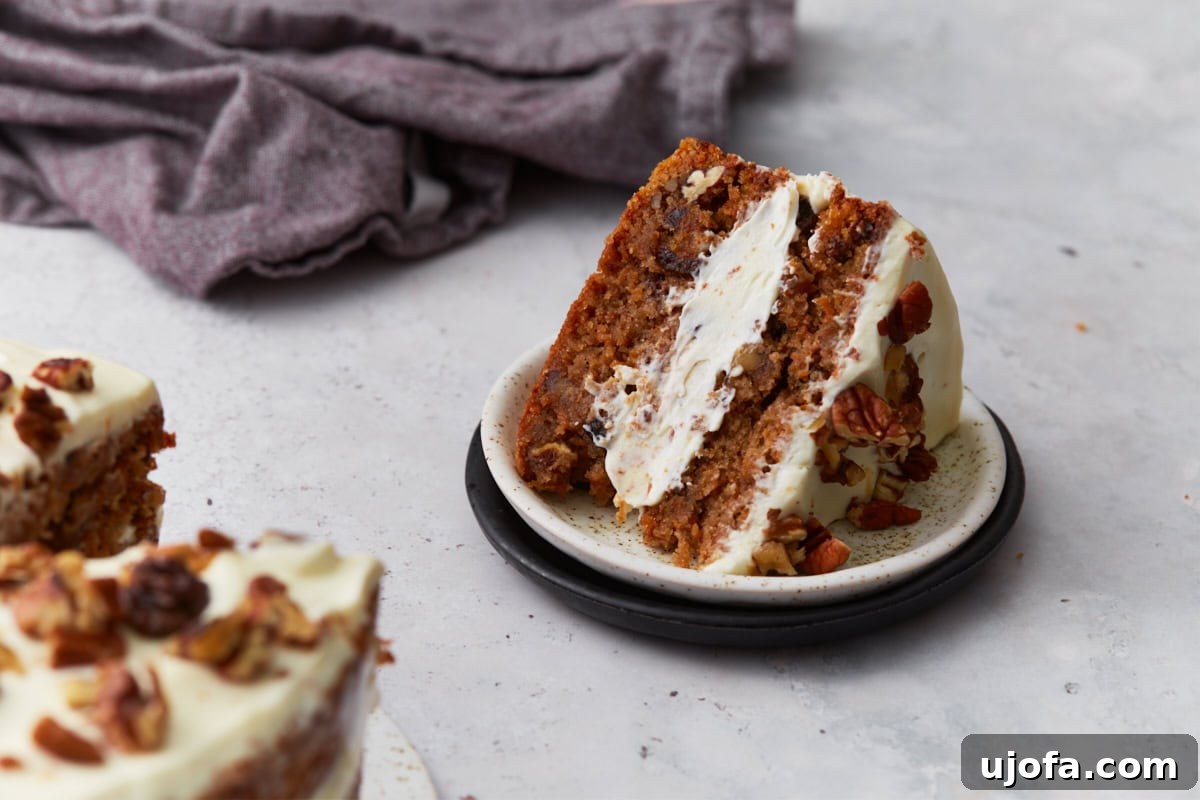 Thick slice of almond flour carrot cake layered with cream cheese frosting and pecans on a small plate.