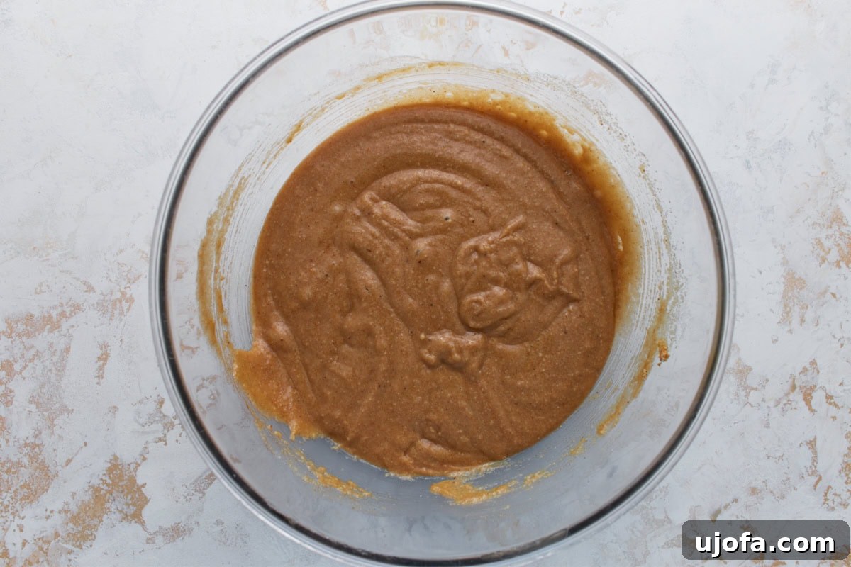Almond flour carrot cake batter partially mixed in a glass bowl, thick and lightly spiced.