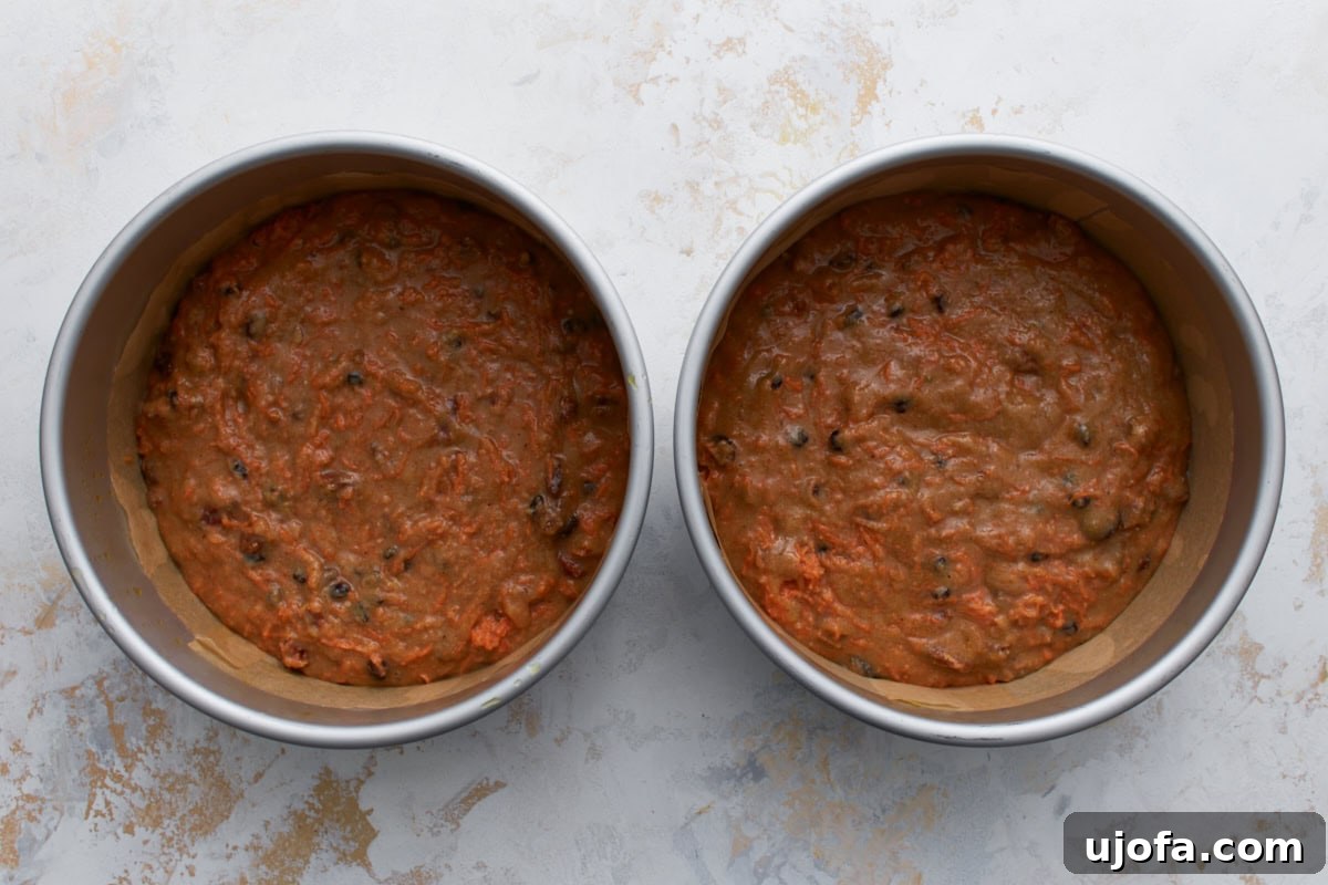 Almond flour carrot cake batter evenly divided between two parchment-lined round cake pans.