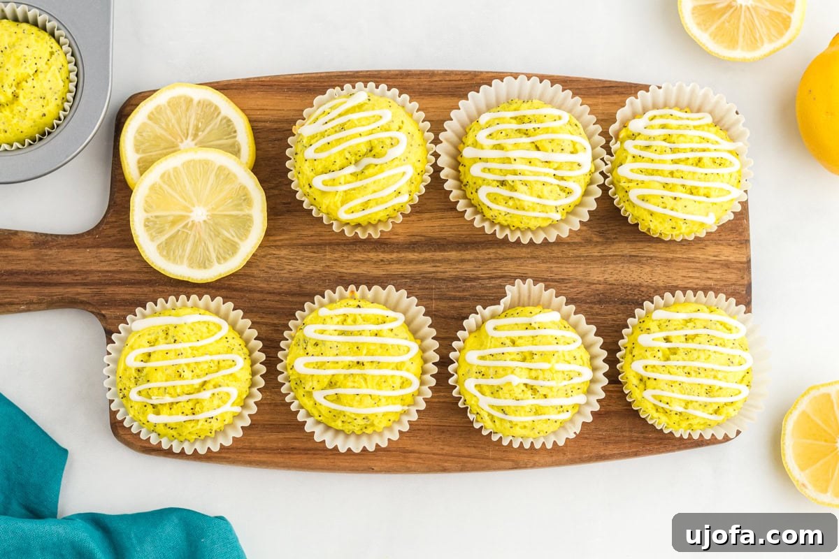 Gluten-free lemon poppy seed muffins with white lemon glaze on wooden board with fresh lemon slices