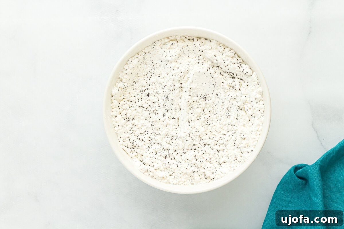 Gluten-free flour mixture with poppy seeds in a white bowl on marble surface