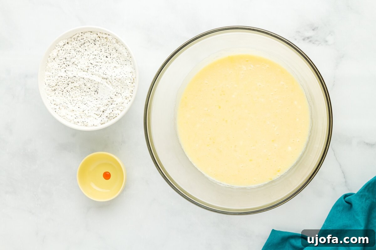 Wet ingredients for gluten-free lemon poppy seed muffins mixed in a large glass bowl with small bowl of food coloring beside it