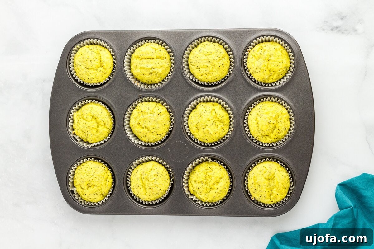 Gluten-free lemon poppy seed muffin batter portioned evenly into lined muffin tin before baking