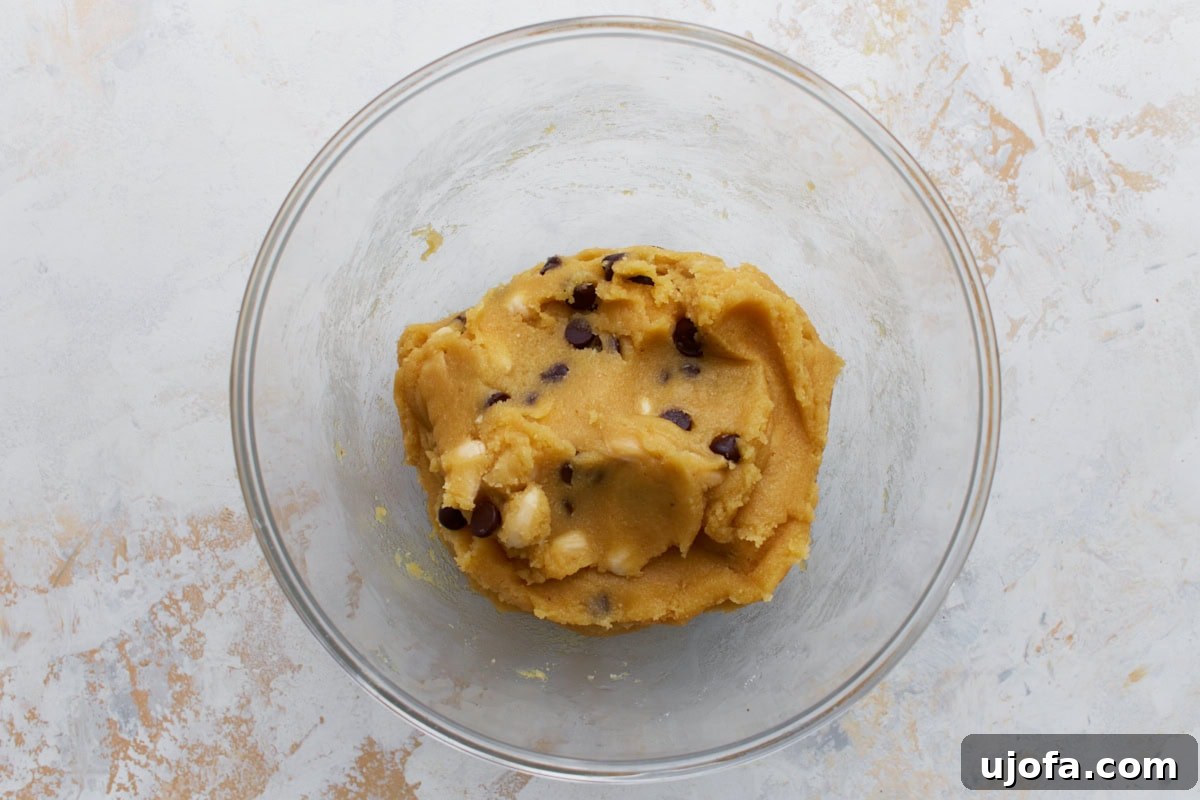Artisanal Almond Biscotti 6 Almond flour biscotti dough in a glass bowl, now containing a generous amount of chocolate chips and sliced almonds, evenly folded in.