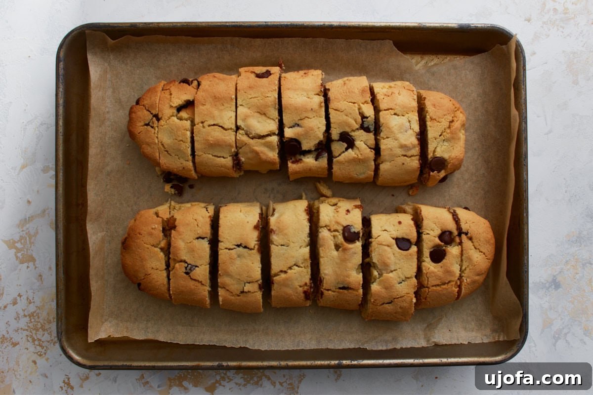 Artisanal Almond Biscotti 8 Baked almond flour biscotti logs, now sliced diagonally into individual pieces, still on the parchment-lined baking sheet after the first bake and initial cooling.